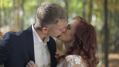 Groom-with-bride-in-the-forest-park.-Wedding-couple.-Making-a-kiss