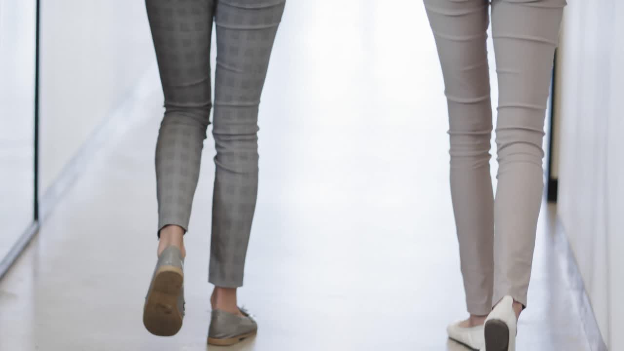 オフィスの廊下で歩いている様々な女性同僚の背中の下部,スローモーション