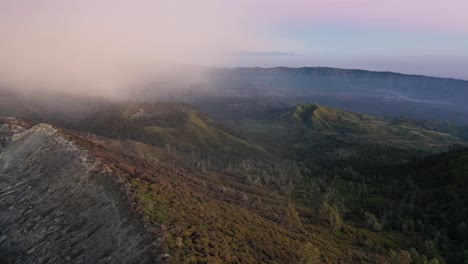 Dramatic-aerial-view-of-a-beautiful-mountain-range-surrounded-by-clouds-during-sunrise