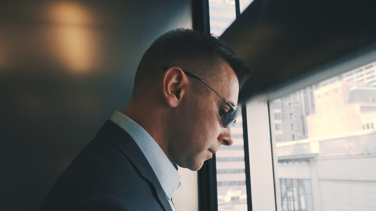 Uomo moderno che scende con l'ascensore dalle pareti trasparenti. Uomo d'affari in ascensore.