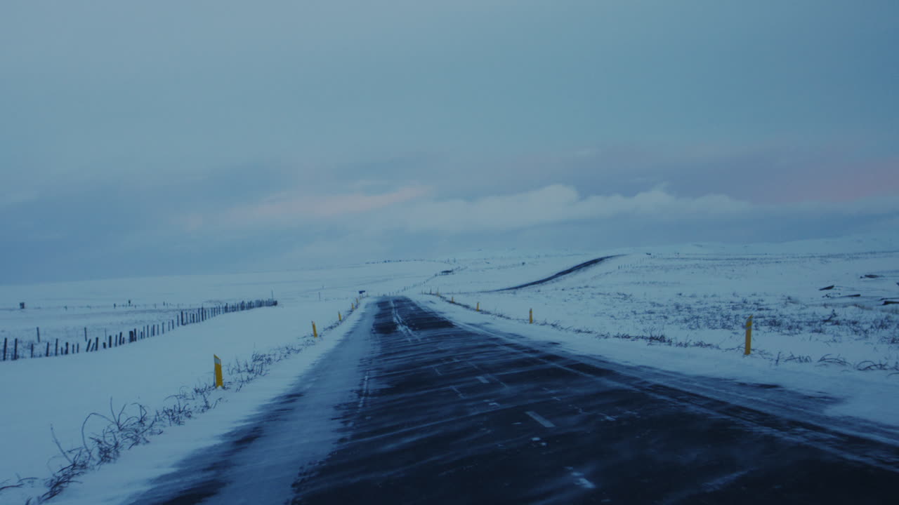 Icelandic Arctic road through snow covered plains under soft light and dramatic skies