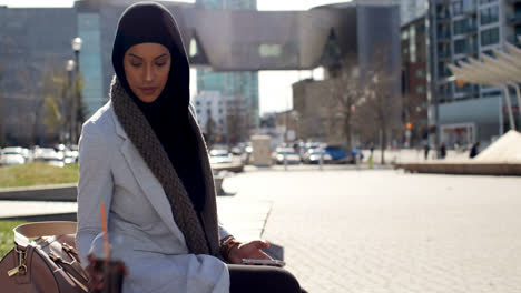 side view of young asian woman in hijab using mobile phone in the city 4k