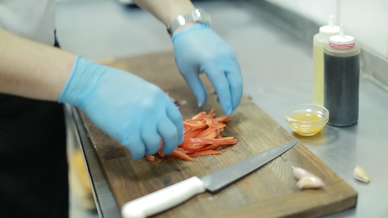 Hand Cutting The Onion and Garlic In The Kitchen. Hand with a knife cutting the onion and garlic on the board in the kitchen