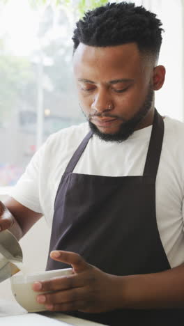 video vertical de un barista afroamericano preparando café en una cafetería