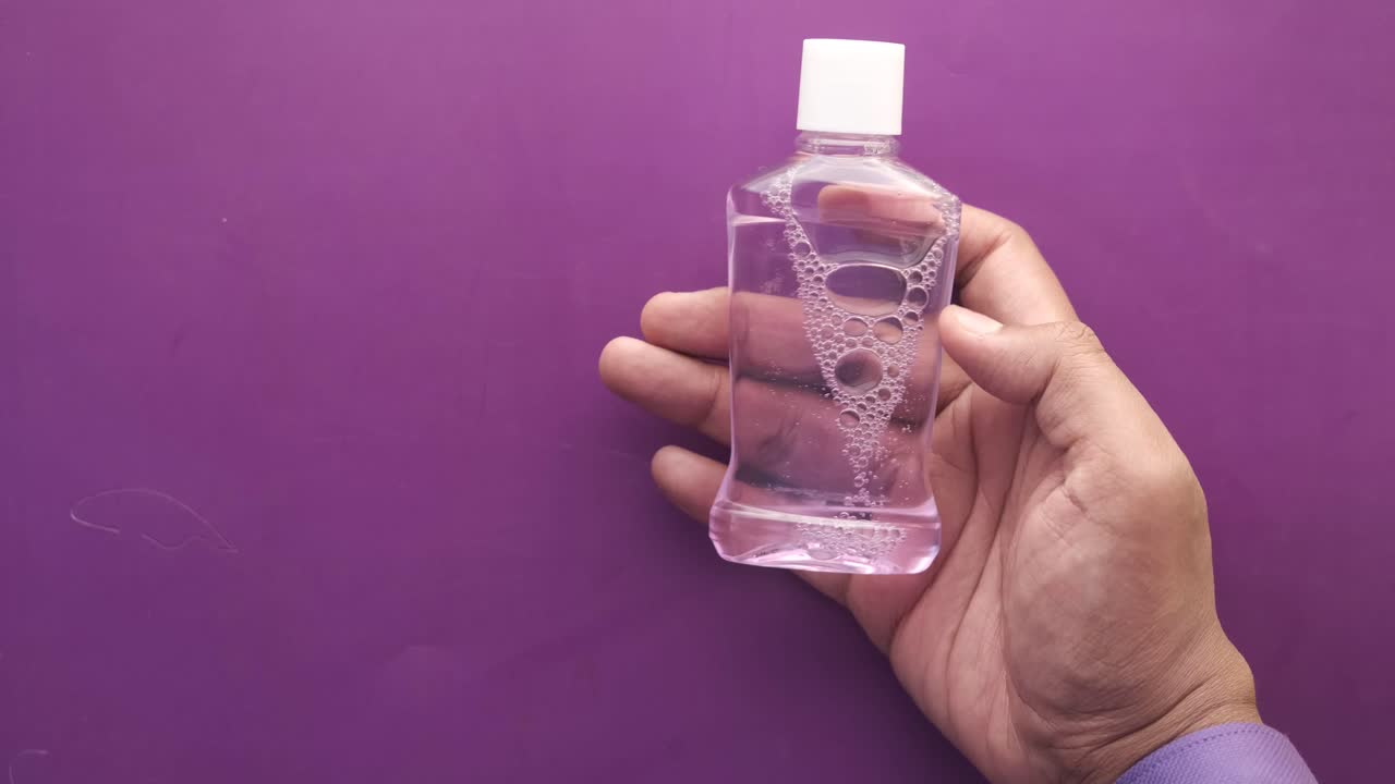 mano con una botella de enjuague bucal