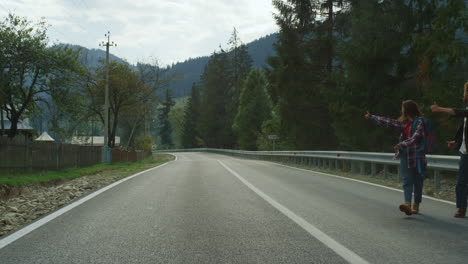 Fröhliche-Touristen-Trampen-Auto-Auf-Der-Autobahn.-Lächelnde-Freunde-Winken-Der-Natur-Zu.