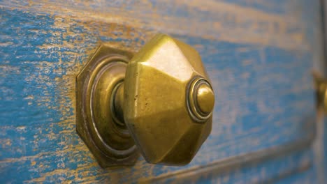 Gold-Metal-Handle-On-An-Old-Wooden-Door-Painted-Blue-in-slowmotion-in-france