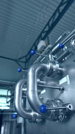 dairy factory with milk pasteurization tank and pipes. motion camera view vertical video