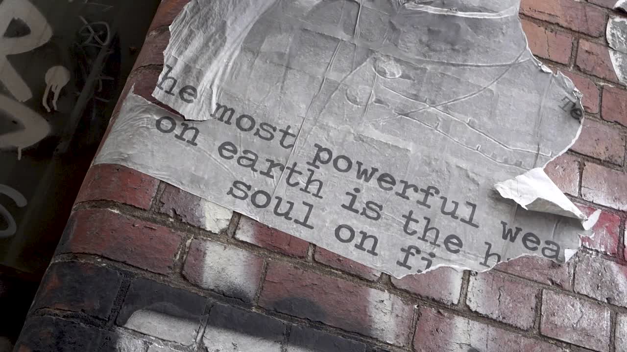 SLOWMO poster peeling off brick wall flaps slowly in the wind