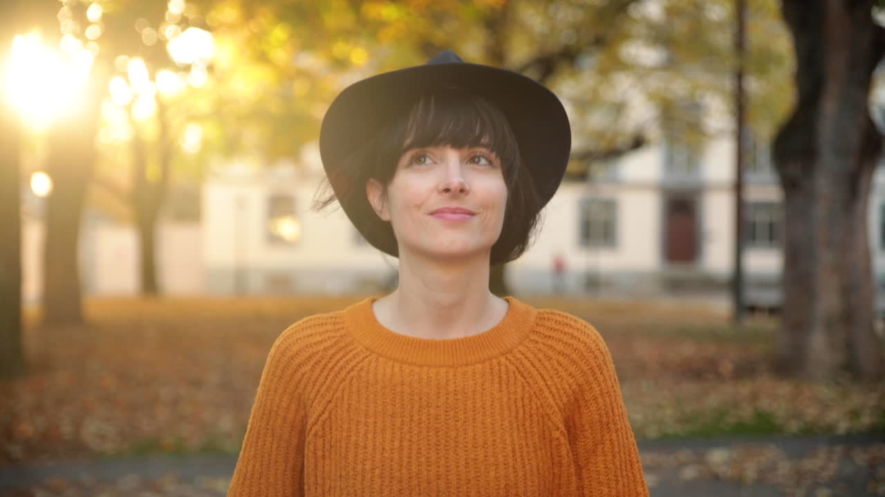 Young brunette woman enjoying a nice walk under trees in autumn during golden hour