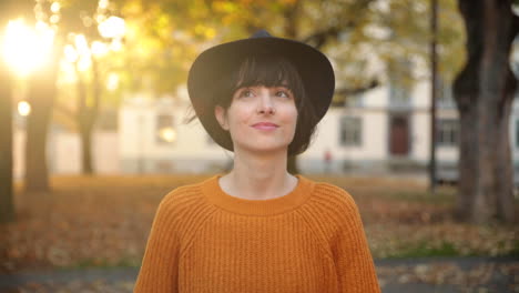 young brunette woman enjoying a nice walk under trees in autumn during golden hour