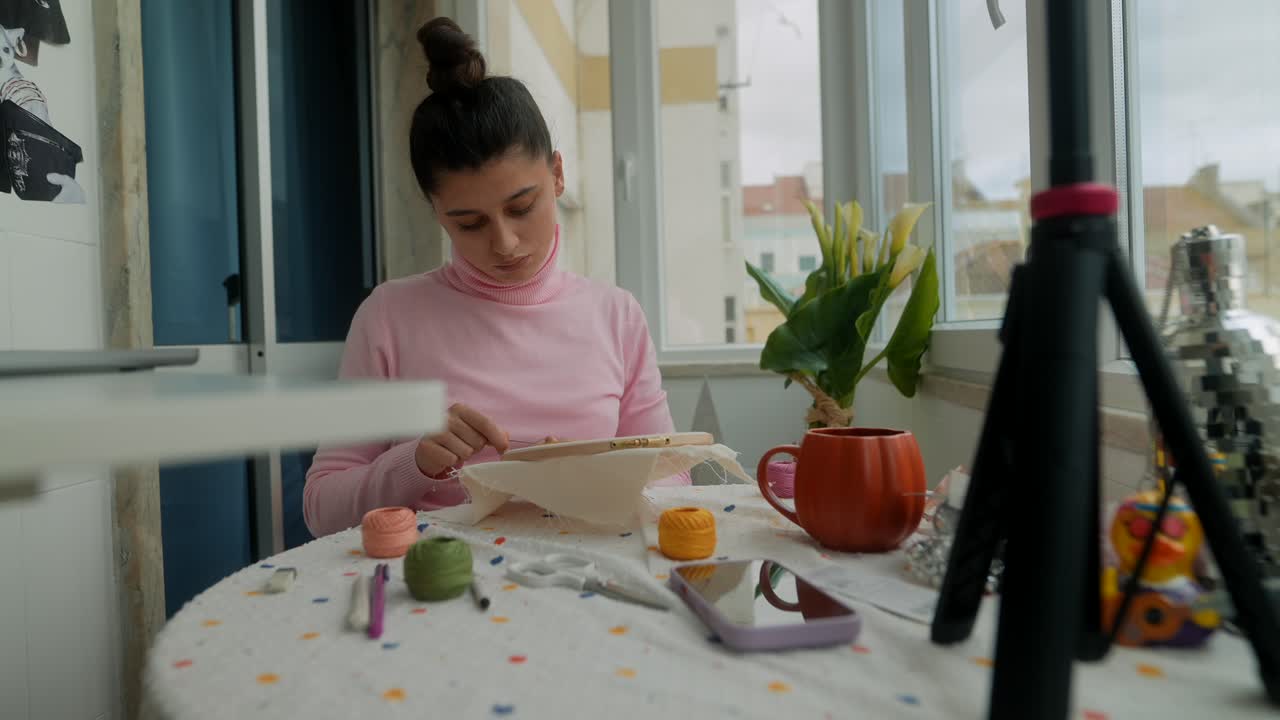 Giovane donna che ricama un motivo con ago e filo