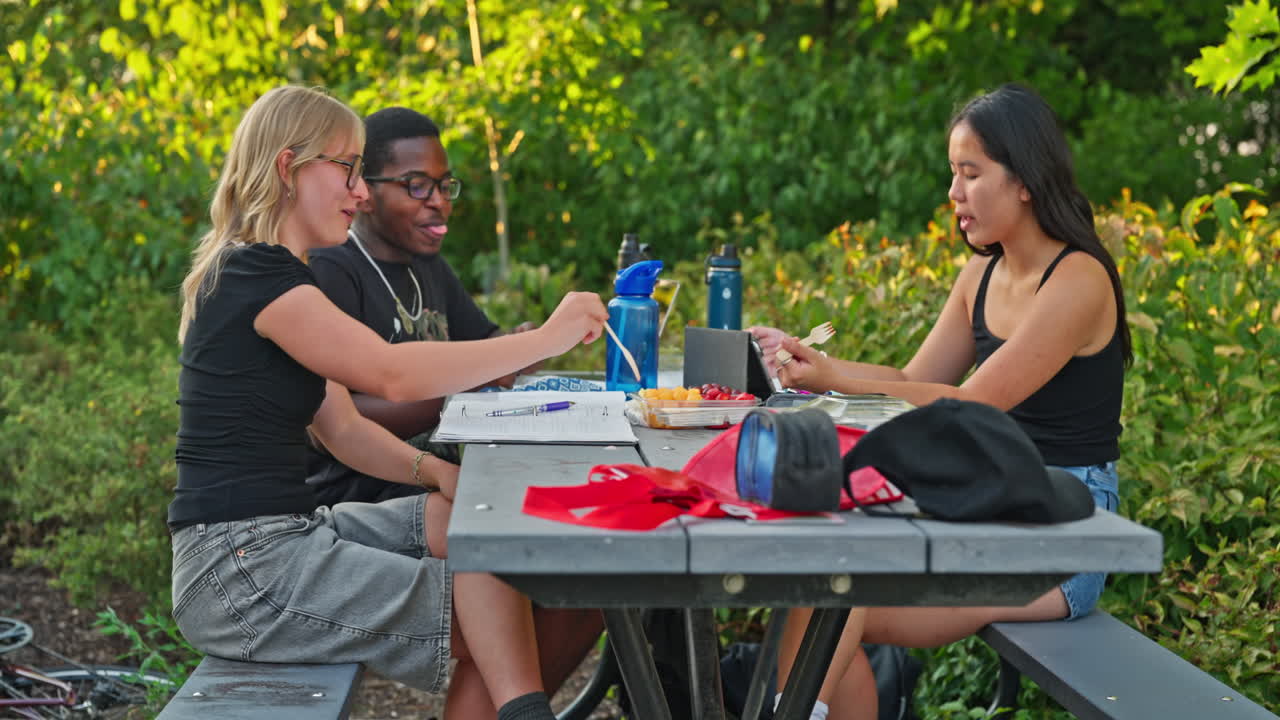 Étudiants soucieux de leur santé mangeant des fruits et étudiant dans un parc public