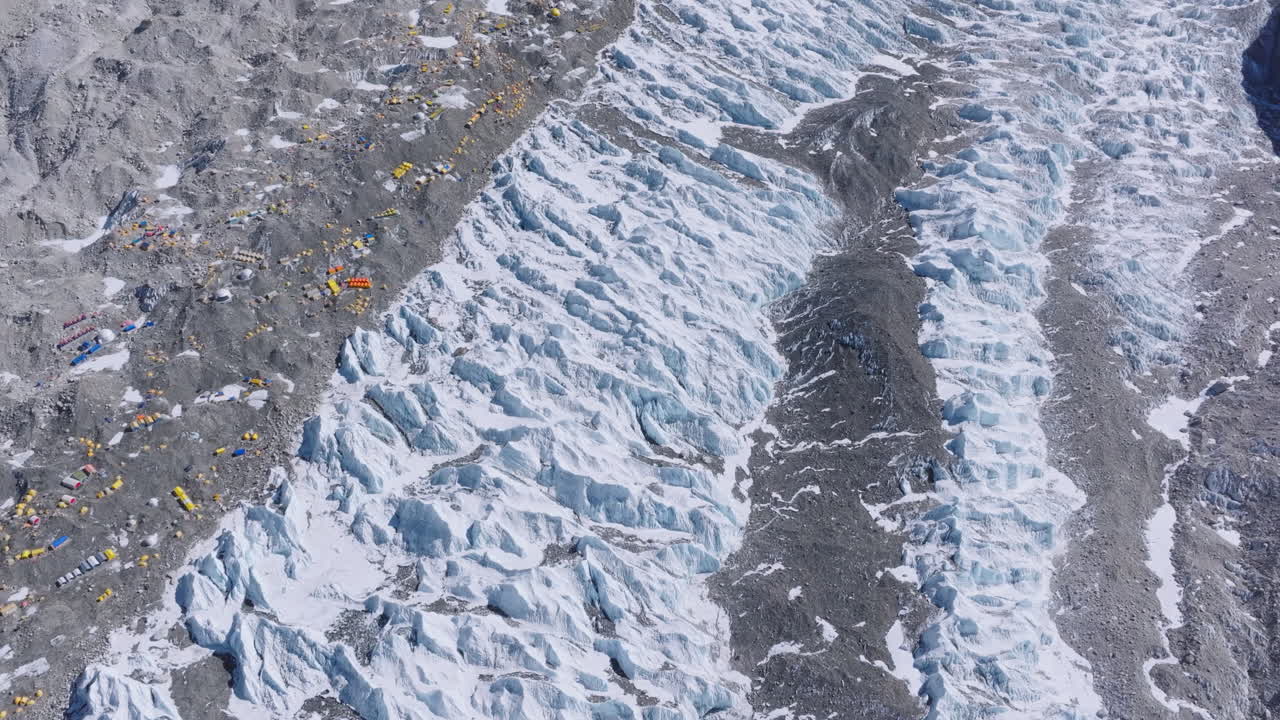 Aerial view of Nepal’s Everest Base Camp, climbers and tourists stay in tents amid dense snow-capped mountains. Highlights scenic beauty, climbing trails, and tent pollution in the fragile Himalayas