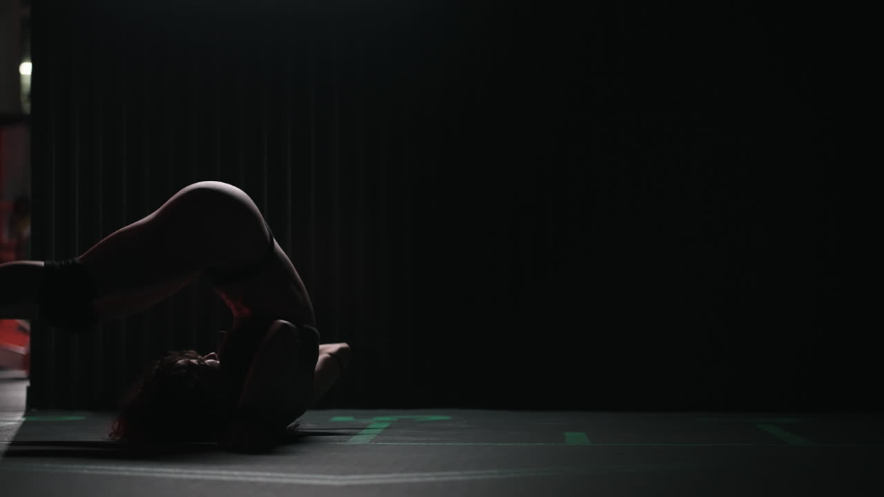 A woman dances beautifully in the dark corridor of the fitness center. A sexy woman in lingerie dances in the gym.