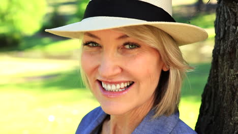 smiling woman leaning against a tree