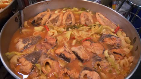 pescado cocinado en una olla grande en el mercado de alimentos de la calle asiática patio de stand para la venta