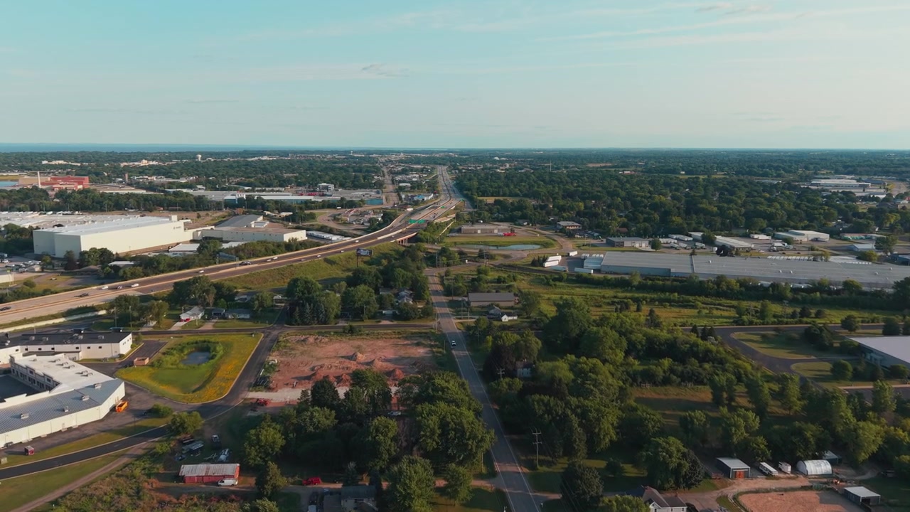 Il trafficato svincolo dell'autostrada 41 passa accanto a magazzini, piccole case e alberi verdi nella calda luce della sera, utile come inquadratura di apertura dell'industria e dei trasporti suburbani, Neenah, Wisconsin.