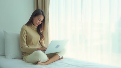 Junge-Asiatische-Frau,-Die-Laptop-Im-Bett-Für-Spaß,-Arbeit,-Studium,-Entspannung-Verwendet