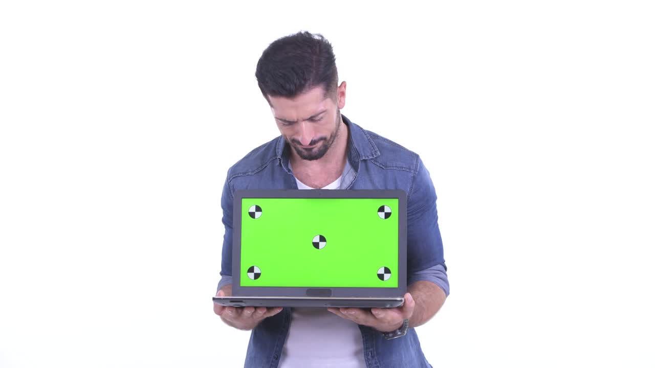 fotografía de estudio de un hombre guapo que se ve triste mientras muestra el espacio de copia de una computadora portátil contra un fondo blanco