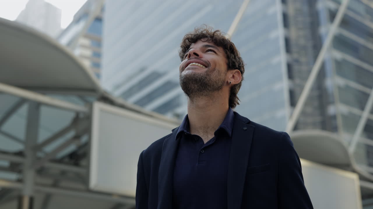 Joven sonriendo y mirando hacia arriba en una ciudad moderna