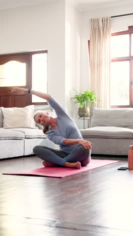 vertical video: senior woman practicing yoga on mat at home, enjoying peaceful exercise