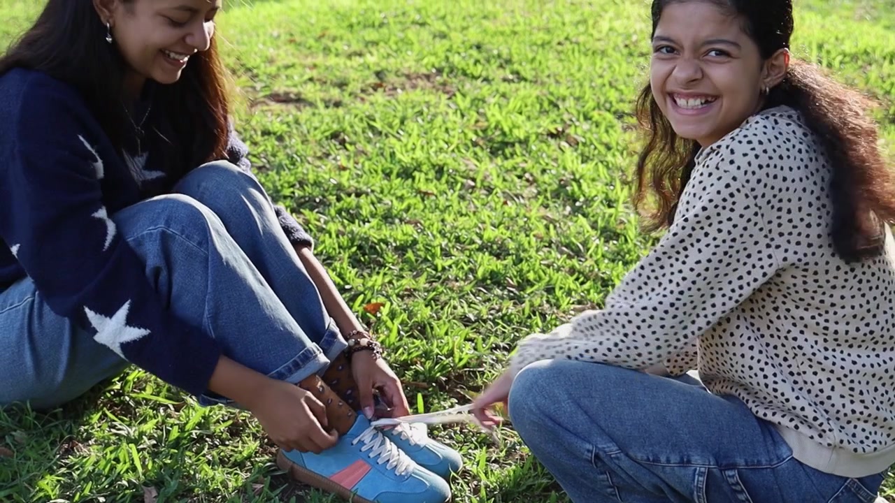 Menina Amarrando os Cadarços da Amiga na Grama Verde