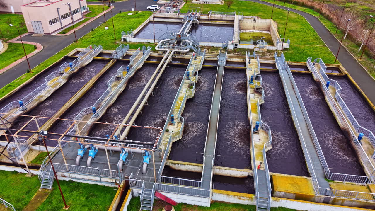 Water treatment facility with multiple processing tanks and water flow observed during daylight hours in an urban area