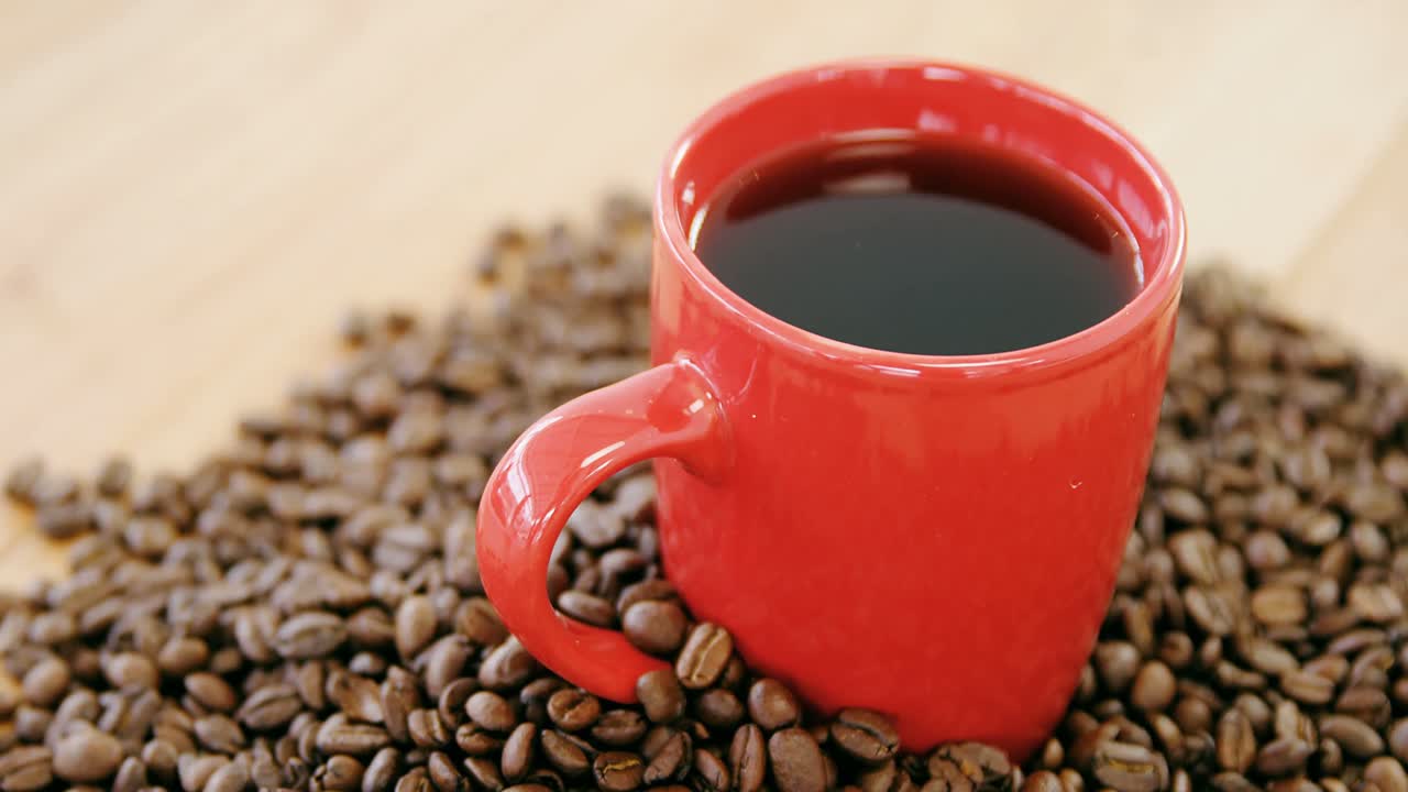 café negro rodeado de granos tostados