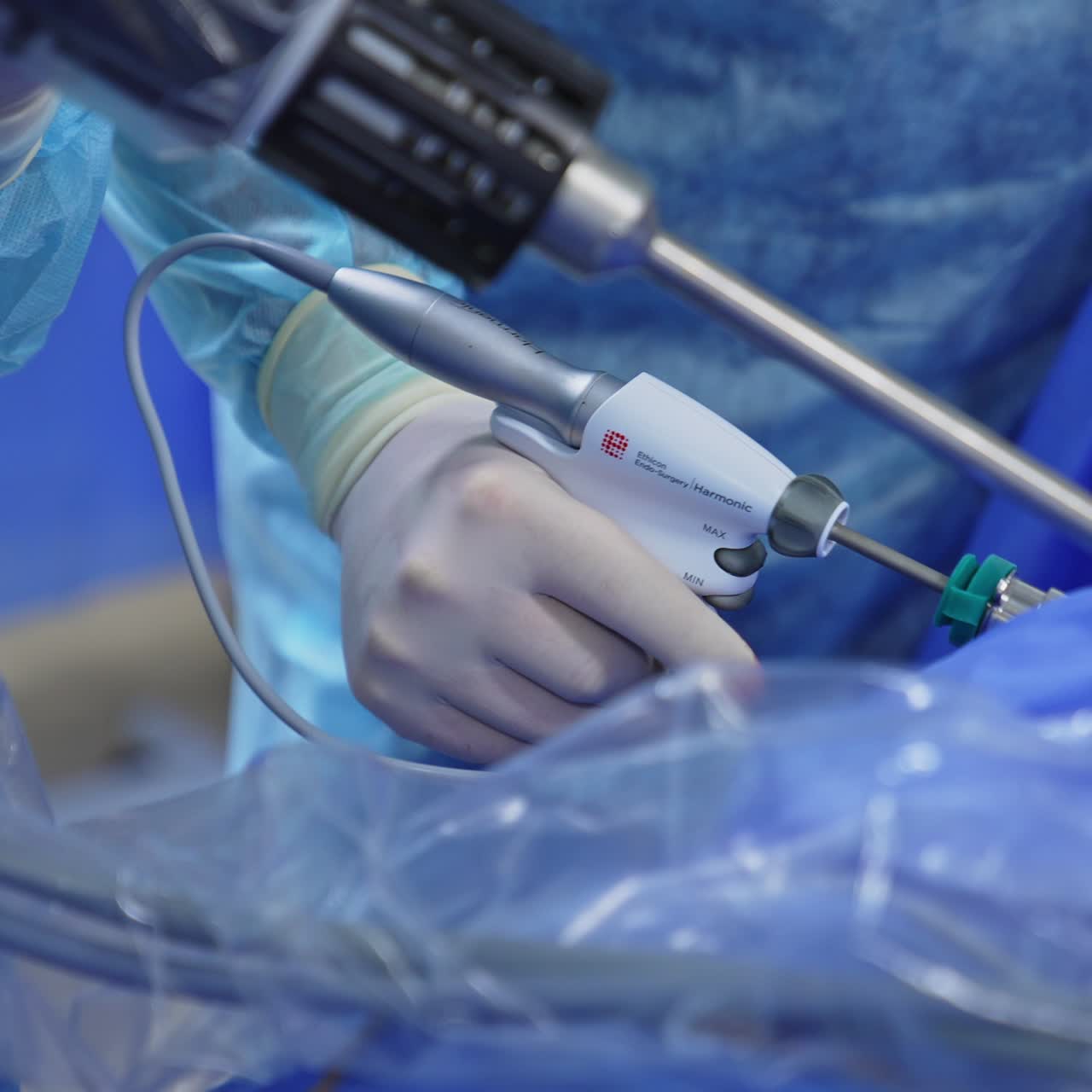 Surgeon uses tool pressing a button and moving it. Assistant doctor holds a device connected to the patient. Close up