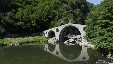 stone arch bridge over river with reflections in green landscape