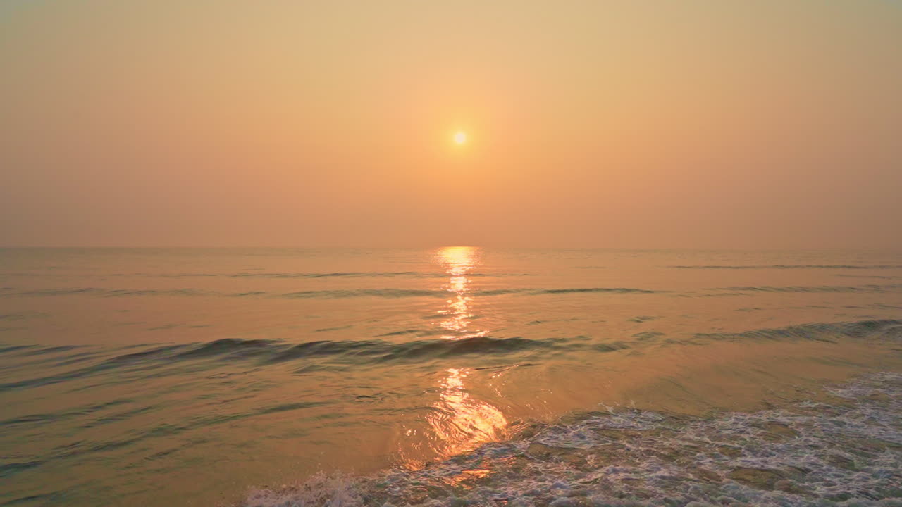 Stunning orange pink sunset at beach, calm sea waves, center static
