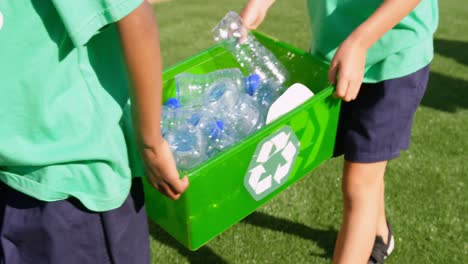 Mid-section-of-schoolkids-carrying-plastic-bottles-waste--in-the-school-playground-4k