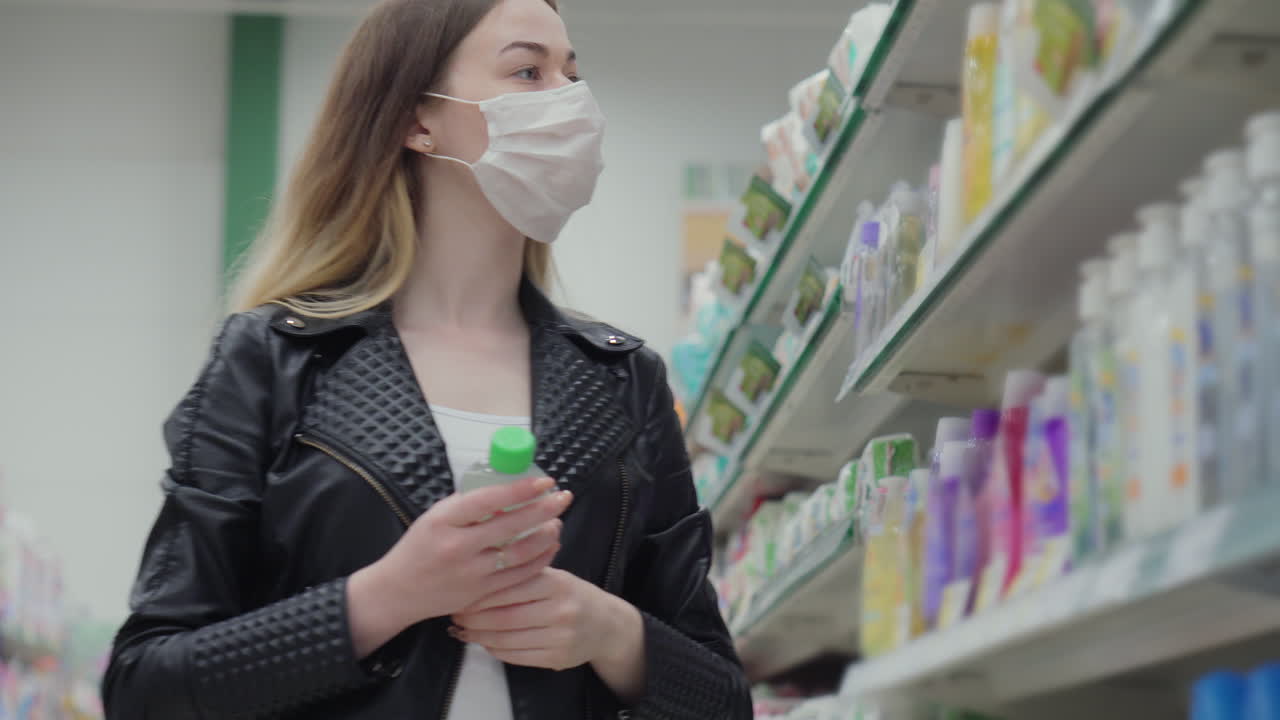 마스크를 착용 한 슈퍼마켓에서 제품을 구매하는 여성