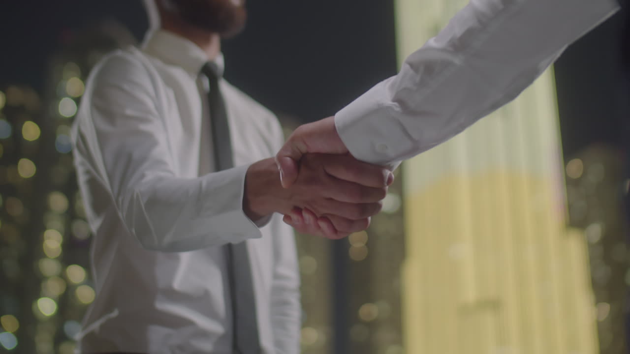 Two Businessmen Shaking Hands in City at Night