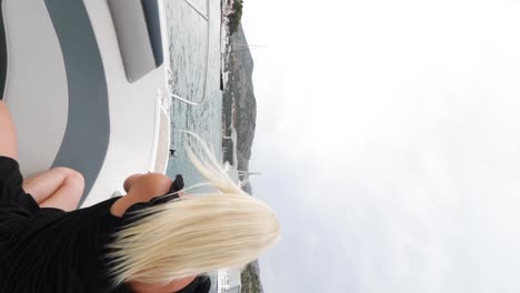 una joven y atractiva mujer caucásica vestida con un vestido negro está sentada y tomando una foto en el mar adriático desde una lancha rápida en croacia