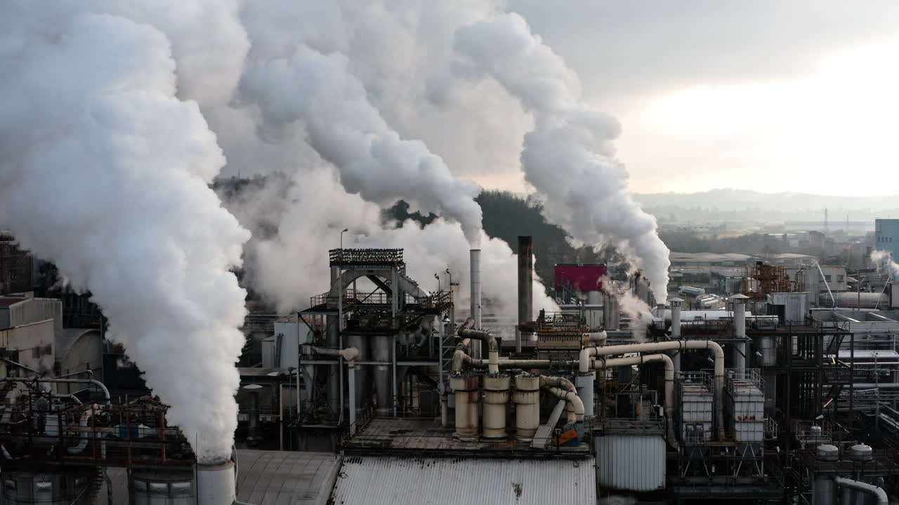 Industrial factory emitting thick white smoke from multiple chimneys, symbolizing pollution