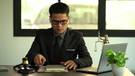 concept of justice and law a male lawyer works in an office with a brass scale goddess on a wooden table. justice hammer with laptop legal concepts and legal services