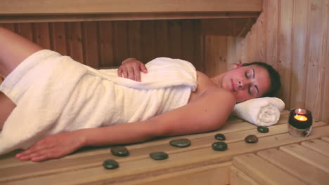 brunette wearing a towel relaxing in the sauna