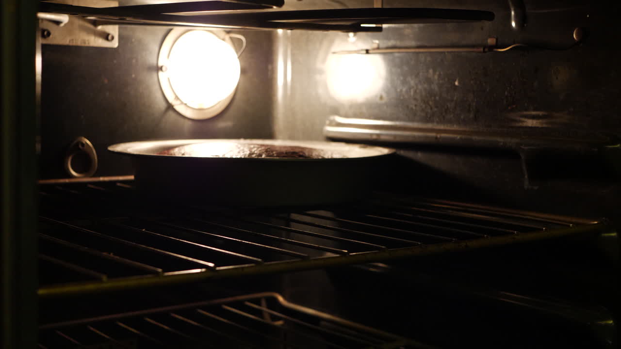 un chef sacando dos moldes de pastel de chocolate del horno después de hornear en la cocina