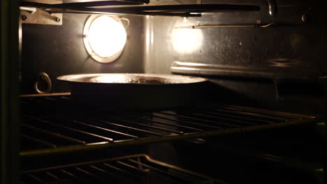 a chef taking two chocolate cake pans out of the oven after baking in the kitchen