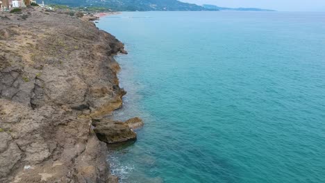 zakynthos greece point st. nicholas rocky cliffs with beautiful clear turquoise water, aerial drone flyover down shot