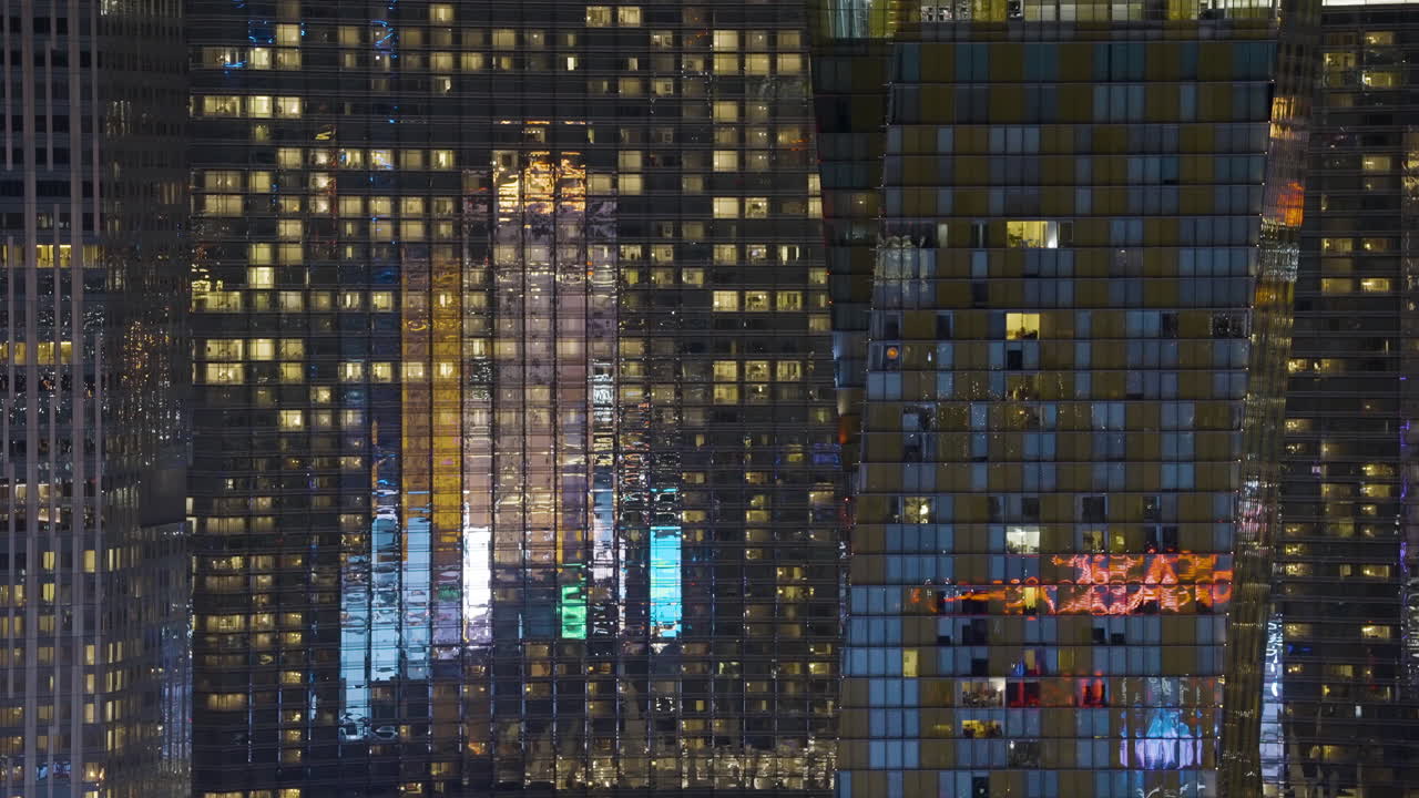 Close-up of modern skyscraper facade at night with illuminated windows and reflections