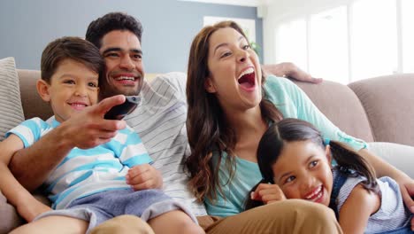 Family-sitting-on-sofa-and-watching-television