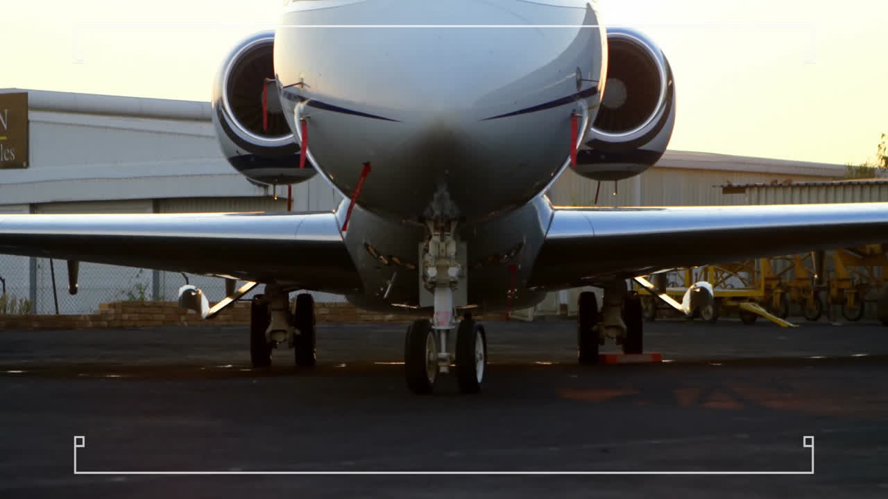 Private jet parked on tarmac, hangar visible in background, ready for flight