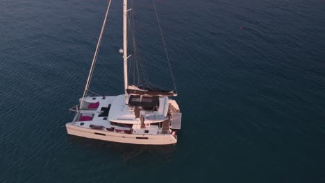 Aerial-view-of-boat-on-calm-sea-with-people-during-sunset,-Cefalu,-Sicily,-Italy