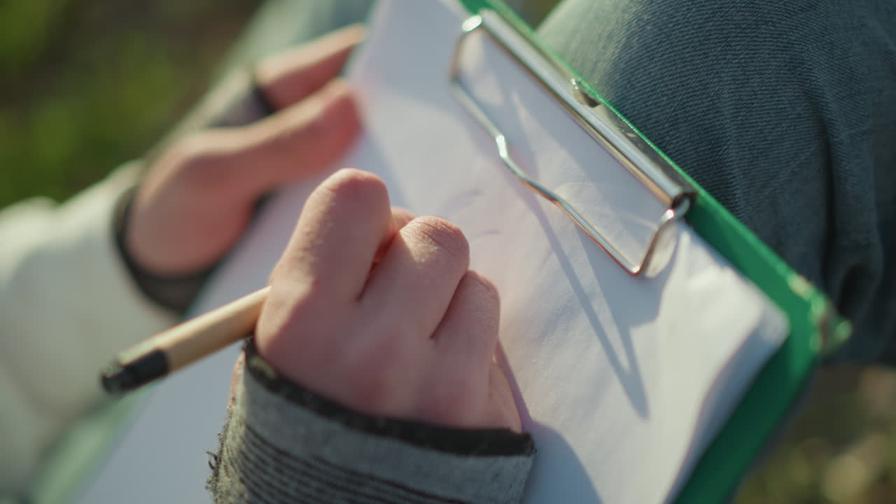 자연 속에서 글쓰기, 햇빛 아래 야외에서 데이터를 기록하는 손, 자연 환경에서 설문 조사 중 관찰 기록, 화창한 날 야외에서 현장 연구를 하면서 필기하기