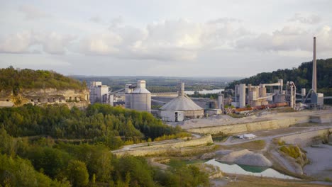 a panoramashot of a quarry surrounded by trees and mountains with a hidden defense fortress in a cloudy setting in the afternoon