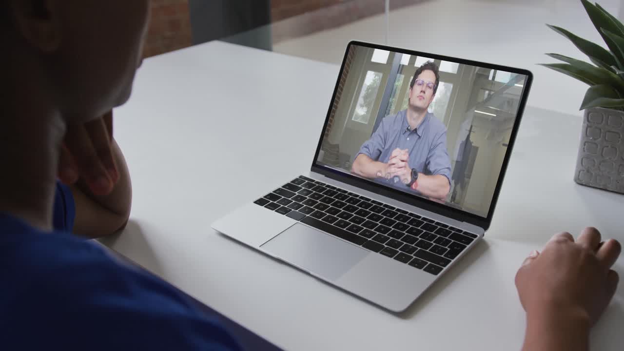 Mid section of african american woman having a video call with male colleague on laptop at office