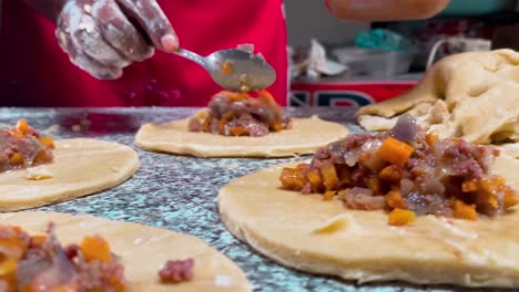 panadero añadiendo rellenos de carne a la masa de la tarta de carne